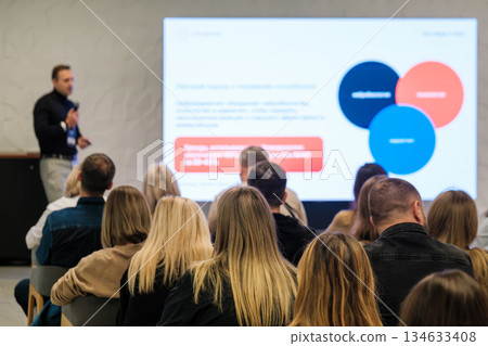 Professional speaker presents slide deck to attentive audience at a conference Professional speaker presents slide deck to attentive audience at a conference 134633408