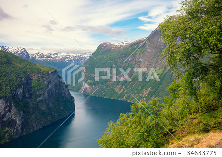 View of the Geiranger fjord on a cloudy day. Rocky shore with frame from trees. Beautiful nature of Norway 134633775