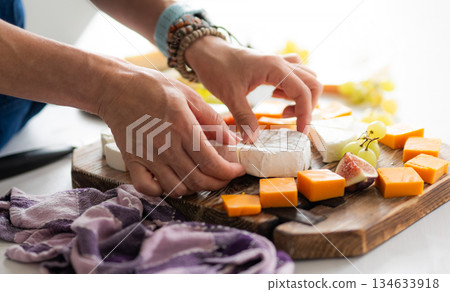 Girl Adding Brie Cheese To Cheese Plate 134633918