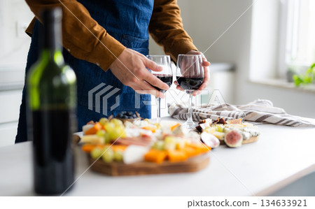 Man In Apron Preparing Wine Glasses And Cheese Board 134633921