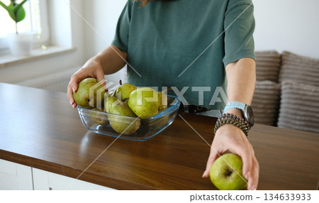 Girl Filling Glass Bowl With Fresh Pears Girl Filling Glass Bowl With Fresh Pears 134633933