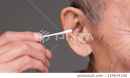 Senior man cleaning his ears with a cotton swab Senior man cleaning his ears with a cotton swab 134634146