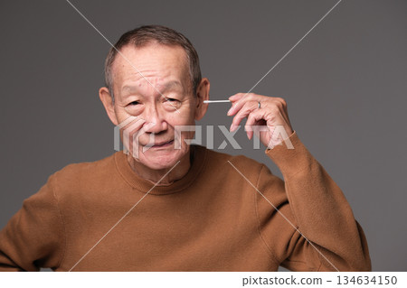 Senior man cleaning his ears with a cotton swab Senior man cleaning his ears with a cotton swab 134634150