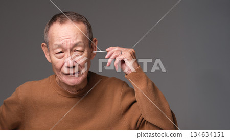 Senior man cleaning his ears with a cotton swab 134634151