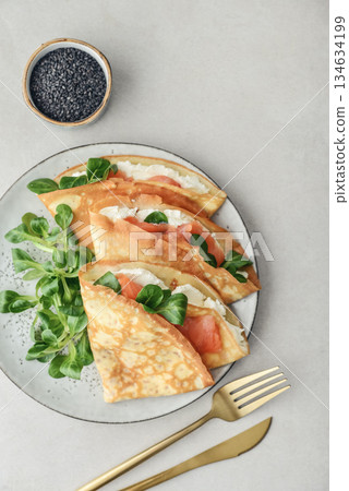 Crepes or thin pancakes with lightly salted salmon, soft cheese and cornsalad Crepes or thin pancakes with lightly salted salmon, soft cheese and cornsalad 134634199