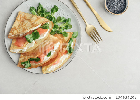 Crepes or thin pancakes with lightly salted salmon, soft cheese and cornsalad Crepes or thin pancakes with lightly salted salmon, soft cheese and cornsalad 134634205