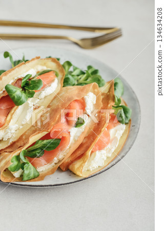 Crepes or thin pancakes with lightly salted salmon, soft cheese and cornsalad Crepes or thin pancakes with lightly salted salmon, soft cheese and cornsalad 134634208