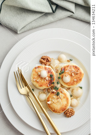 cottage cheese pancakes, syrniki, curd fritters served with pear balls, walnut and honey 134634211