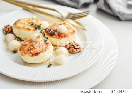 cottage cheese pancakes, syrniki, curd fritters served with pear balls, walnut and honey 134634214