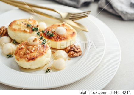 cottage cheese pancakes, syrniki, curd fritters served with pear balls, walnut and honey 134634215
