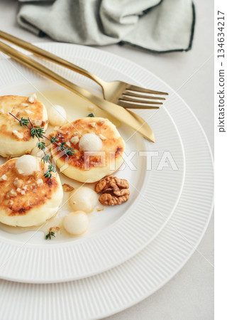 cottage cheese pancakes, syrniki, curd fritters served with pear balls, walnut and honey cottage cheese pancakes, syrniki, curd fritters served with pear balls, walnut and honey 134634217