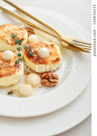 cottage cheese pancakes, syrniki, curd fritters served with pear balls, walnut and honey 134634233