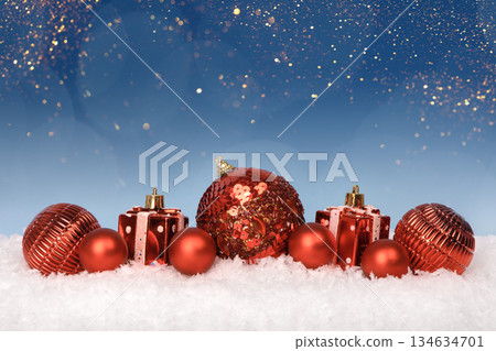 Christmas tree baubles on blue background with white snow and golden lights. Festive winter holiday background. Design with copy space for greeting card, text, advertising, banner, invitation Christmas tree baubles on blue background with white snow and golden lights. Festive winter holiday background. Design with copy space for greeting card, text, advertising, banner, invitation 134634701