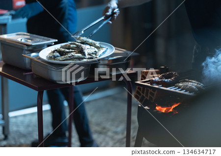 Person serving fresh grilled fish at outdoor barbecue 134634717