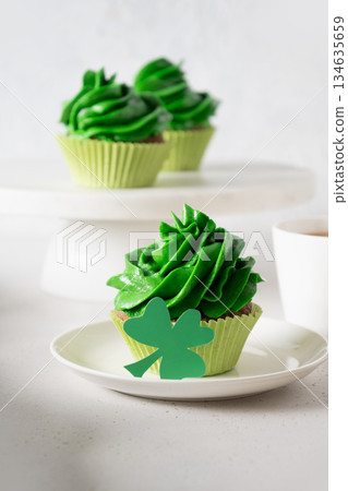 St. Patrick's Day tasty cupcake with green whipped cream decorated clover on white background. Close up. Vertical format. 134635659