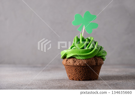 St. Patrick's Day cupcake with green whipped cream decorated clover on gray background. Copy space. Close up. Festive food. 134635660