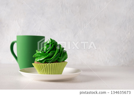 St. Patrick's Day with cup of Irish coffee, chocolate cupcakes decorated green whipped cream and clover on white background for festive holiday. Close up. Copy space. St. Patrick's Day with cup of Irish coffee, chocolate cupcakes decorated green whipped cream and clover on white background for festive holiday. Close up. Copy space. 134635673
