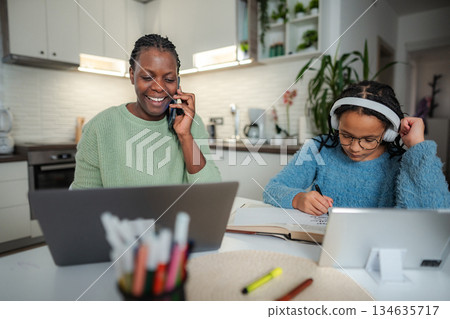 Mother multitasking working from home while daughter remote learning Mother multitasking working from home while daughter remote learning 134635717