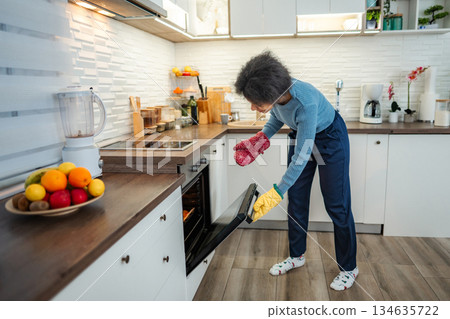 Woman baking food in modern kitchen oven Woman baking food in modern kitchen oven 134635722