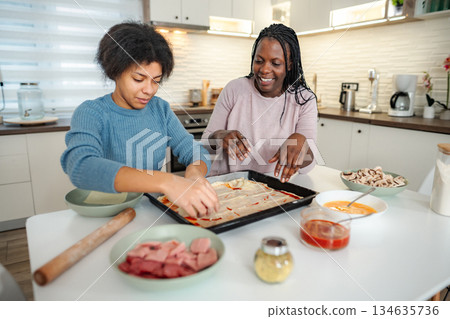Mother and daughter making homemade pizza together in kitchen Mother and daughter making homemade pizza together in kitchen 134635736