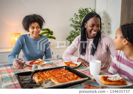 African American family enjoying pizza dinner at home African American family enjoying pizza dinner at home 134635737