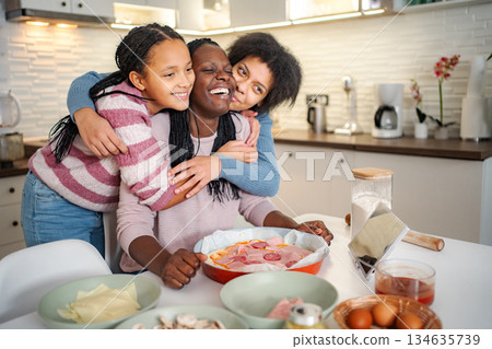 Black mother and daughters enjoying cooking pizza together Black mother and daughters enjoying cooking pizza together 134635739