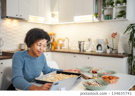 Woman baking pizza following online recipe on tablet Woman baking pizza following online recipe on tablet 134635741