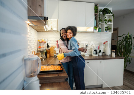 African American mother and daughter embracing with love in kitchen African American mother and daughter embracing with love in kitchen 134635761
