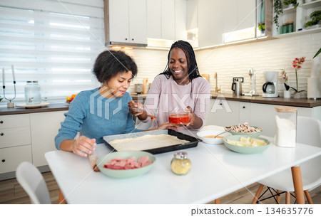Mother and daughter making homemade pizza in kitchen Mother and daughter making homemade pizza in kitchen 134635776
