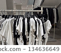 Minimalist black and white basic t shirts hang neatly on a rack inside a modern clothing store 134636649