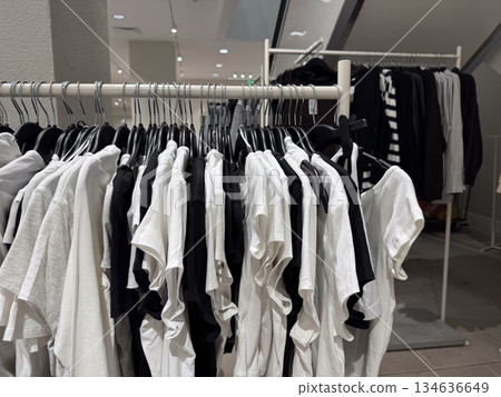 Minimalist black and white basic t shirts hang neatly on a rack inside a modern clothing store 134636649