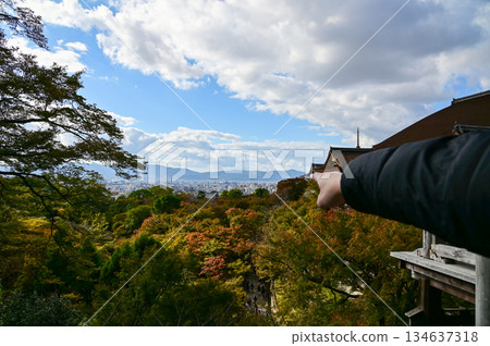 A man is pointing to the Kyoto city from kiyomizu-dera temple in Kyoto, Japan. Major tourist attraction in Kansai region in Japan. Travel concept. Japan cityscape. A man is pointing to the Kyoto city from kiyomizu-dera temple in Kyoto, Japan. Major tourist attraction in Kansai region in Japan. Travel concept. Japan cityscape. 134637318