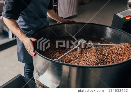 Unrecognizable worker is controlling the process of cooling fresh roasted coffee beans Unrecognizable worker is controlling the process of cooling fresh roasted coffee beans 134638432