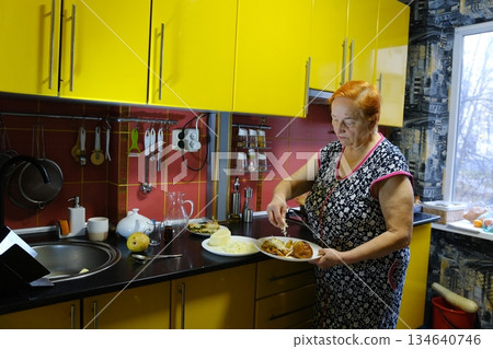 Senior woman cooking food on the stove in kitchen Senior woman cooking food on the stove in kitchen 134640746