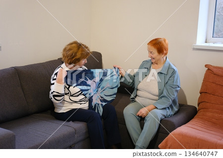 Two mature women friends mother and daughter using smartphone while sitting on sunny terrace of country house Two mature women friends mother and daughter using smartphone while sitting on sunny terrace of country house 134640747