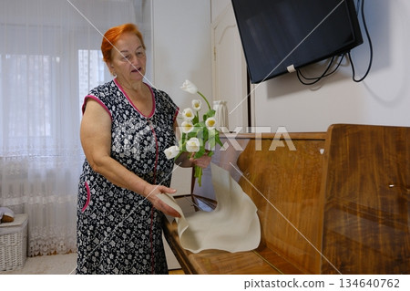 Happy International Womens Day, 8 March gift. Senior woman smells bouquet of eustoma flowers at home. Surprise present for spring holiday 134640762