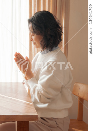 一位中年婦女在家中為逝者祈禱。 一位中年婦女在家中為逝者祈禱。 134641799