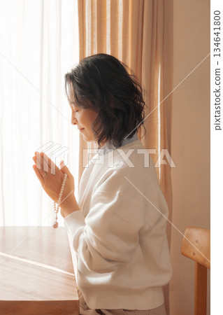 一位中年婦女在家中為逝者祈禱。 134641800