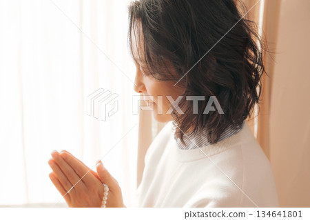 一位中年婦女在家中為逝者祈禱。 134641801