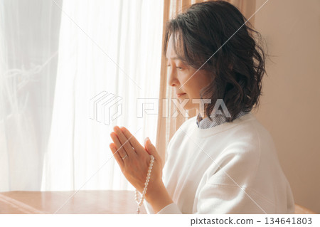 一位中年婦女在家中為逝者祈禱。 134641803