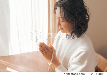 A middle-aged woman praying for the deceased at home 134641805