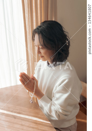 一位中年婦女在家中為逝者祈禱。 134641807