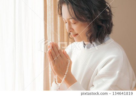 一位中年婦女在家中為逝者祈禱。 134641819