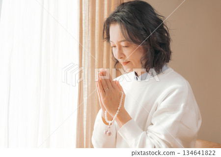 一位中年婦女在家中為逝者祈禱。 134641822