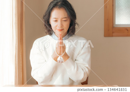A middle-aged woman praying for the deceased at home 134641831