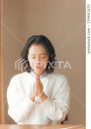 一位中年婦女在家中為逝者祈禱。 134641835