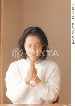 一位中年婦女在家中為逝者祈禱。 一位中年婦女在家中為逝者祈禱。 134641836