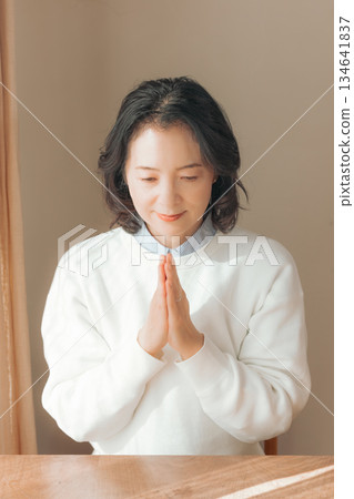 一位中年婦女在家中為逝者祈禱。 134641837