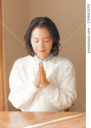 一位中年婦女在家中為逝者祈禱。 134641839