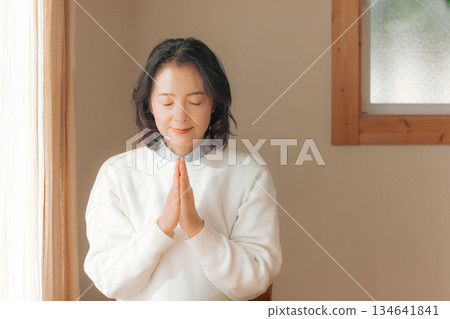 一位中年婦女在家中為逝者祈禱。 134641841